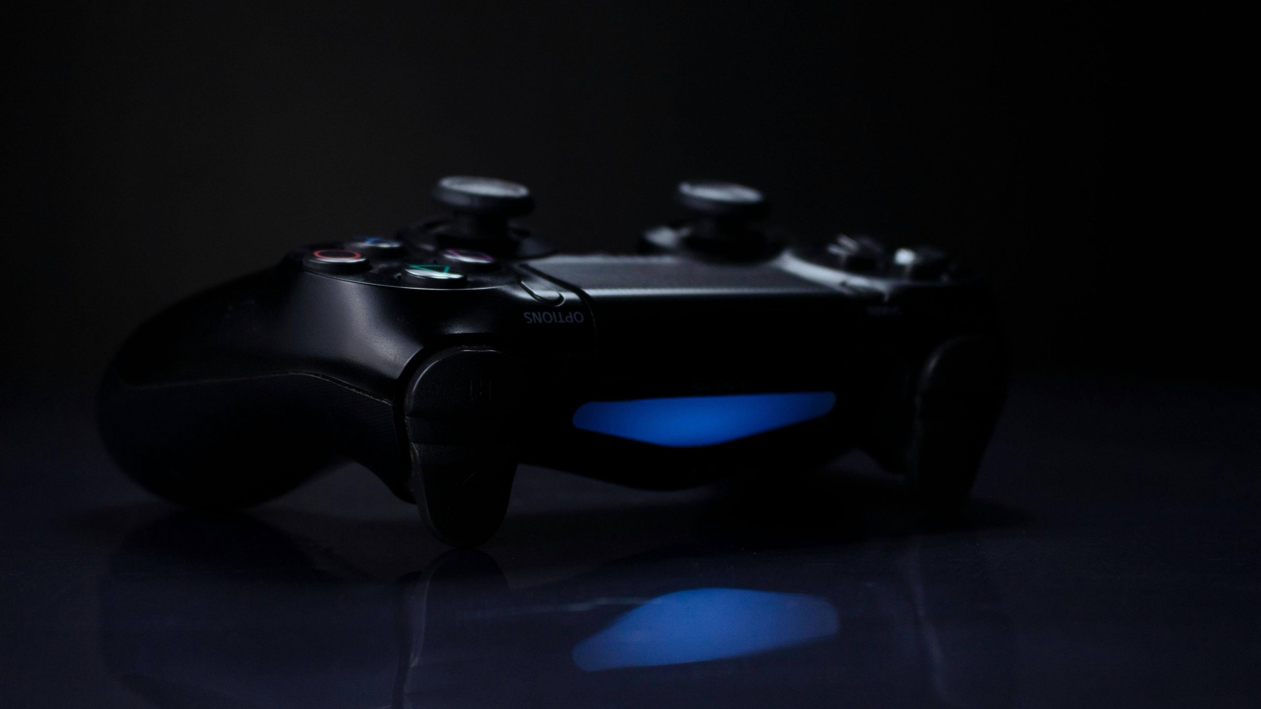 A Playstation 5 controller in a dark room with it's blue light illuminating the surface