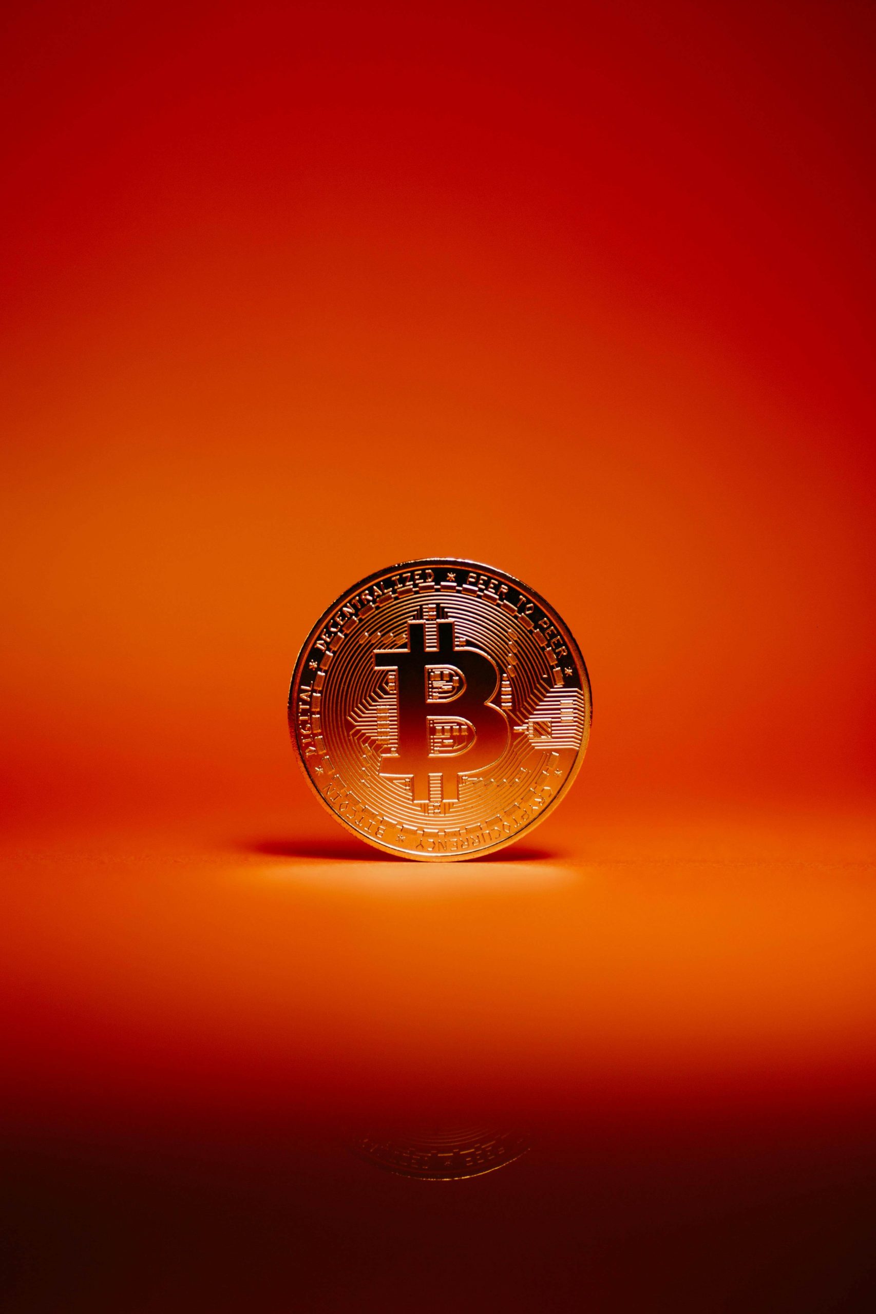 A single bitcoin standing vertically with an orange background behind it.