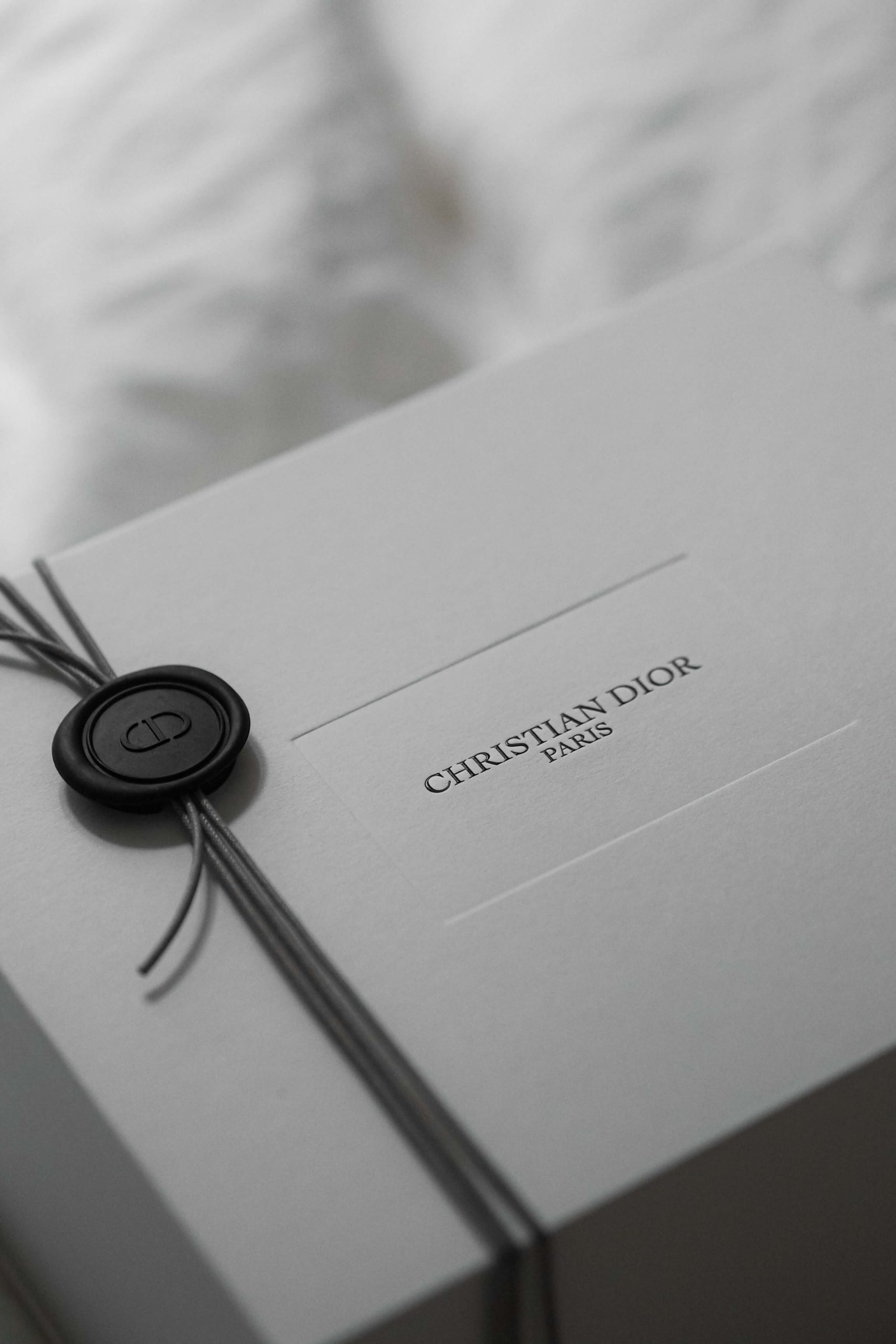 A Christian Dior branded box sat on a bed in a black and white picture